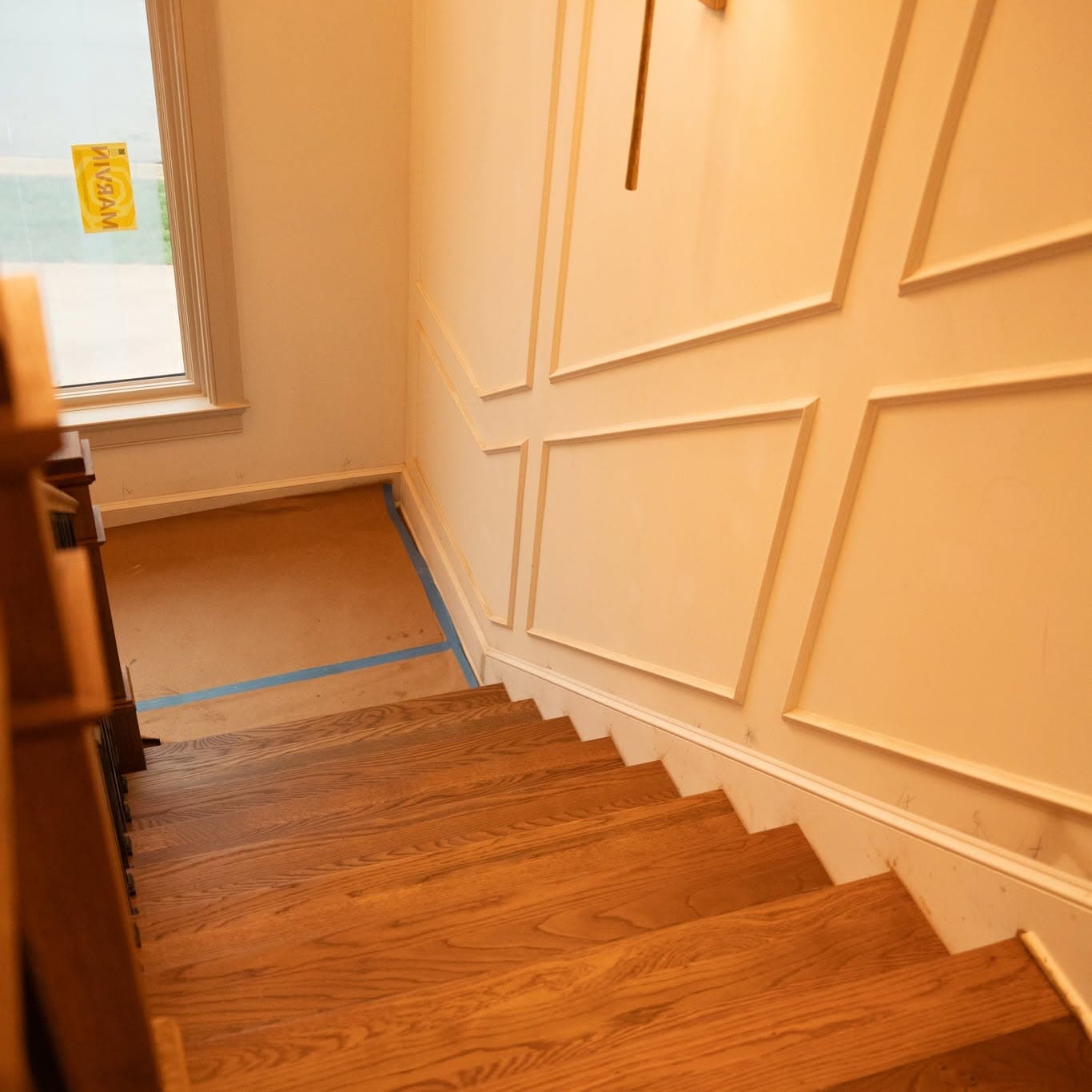 Looking down a hardwood staircase with matching treads and handrail, a square wood newel, and matte black metal balusters, a job by Alabama Hardwood Restoration