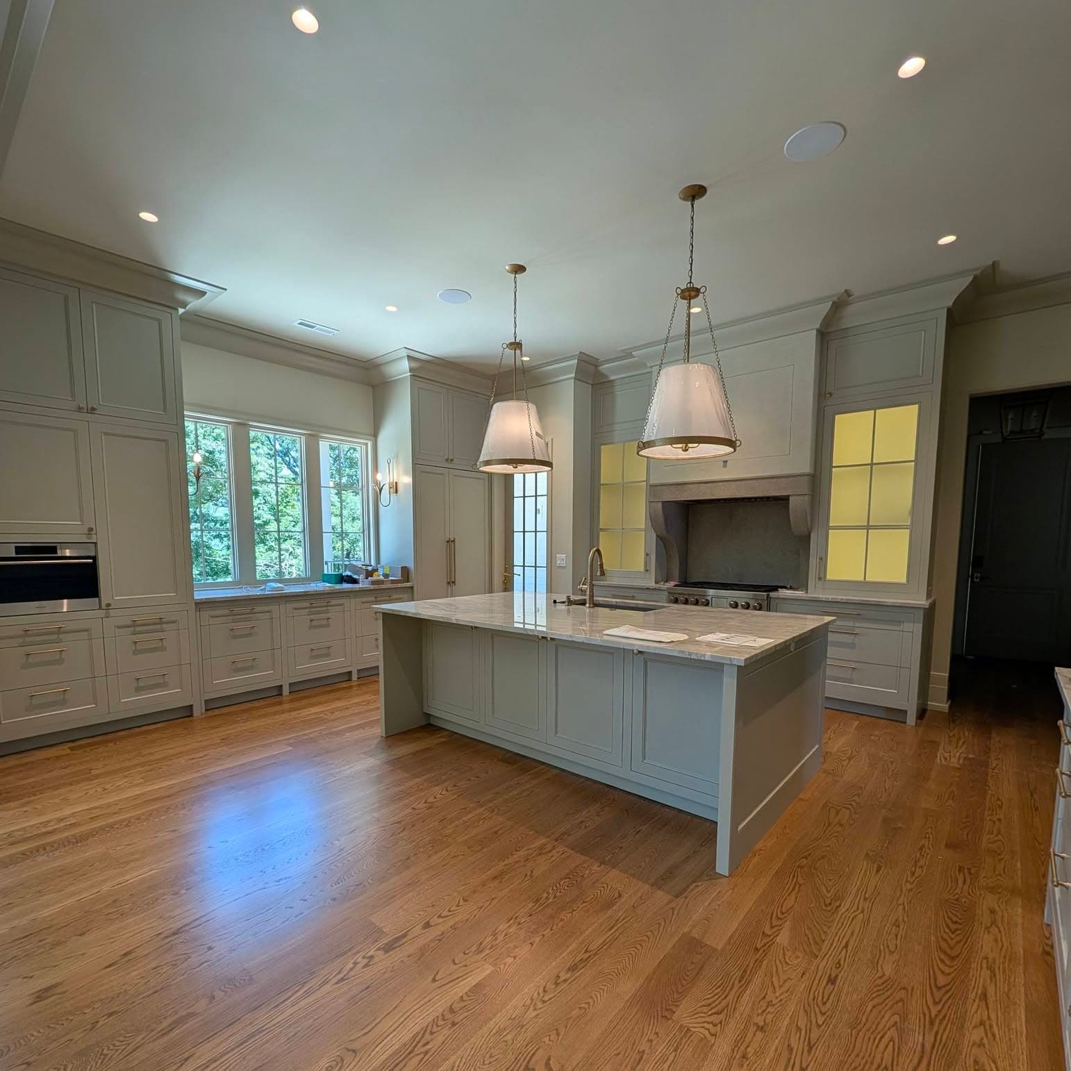 Wide-plank oak hardwood floor in a kitchen with a large island and pendant lights, a job by Alabama Hardwood Restoration
