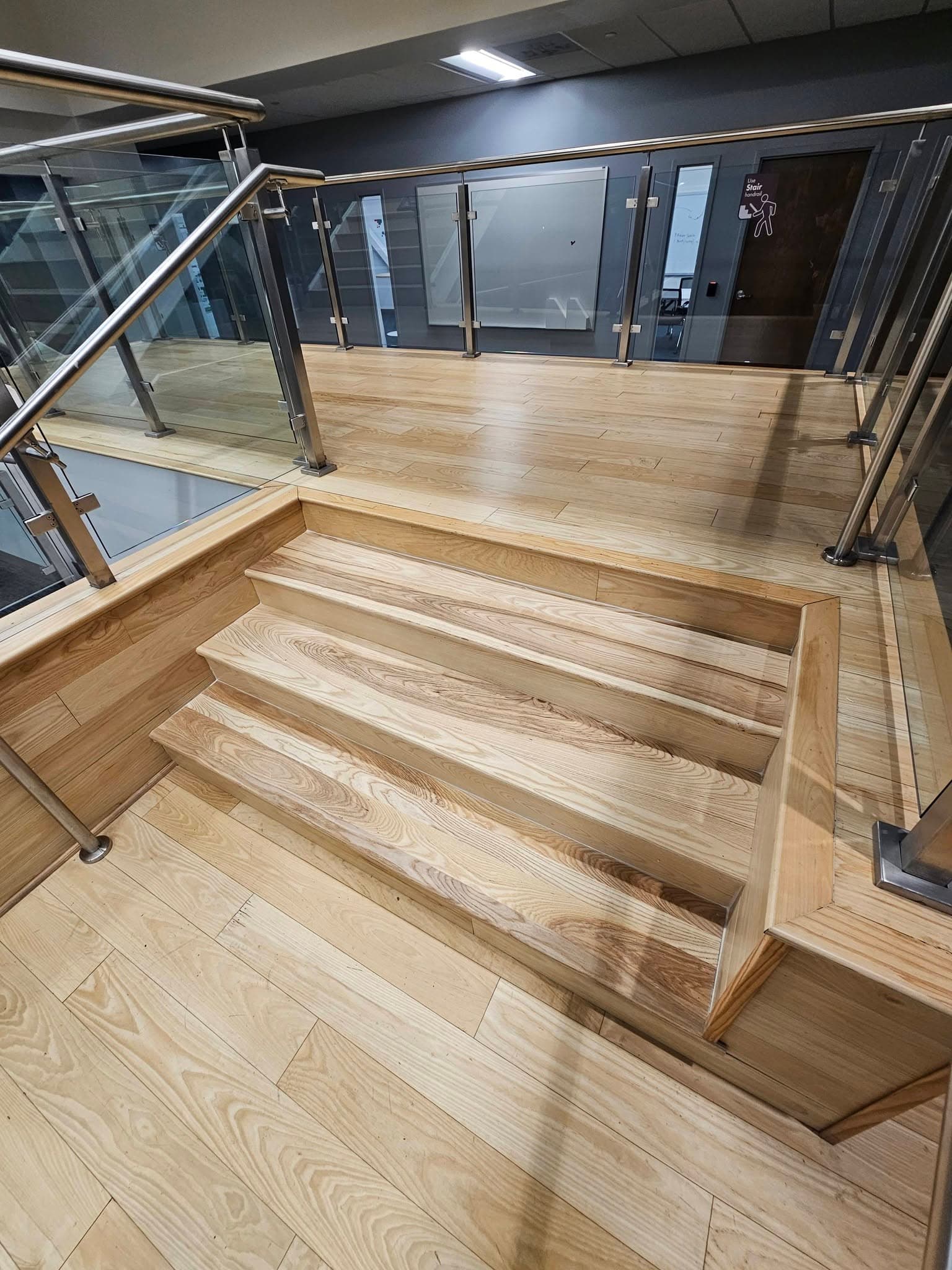 Wide view of a hardwood landing and short commercial stairs at Mazda Toyota manufacturing in North Alabama, a stair replacement by Alabama Hardwood Restoration