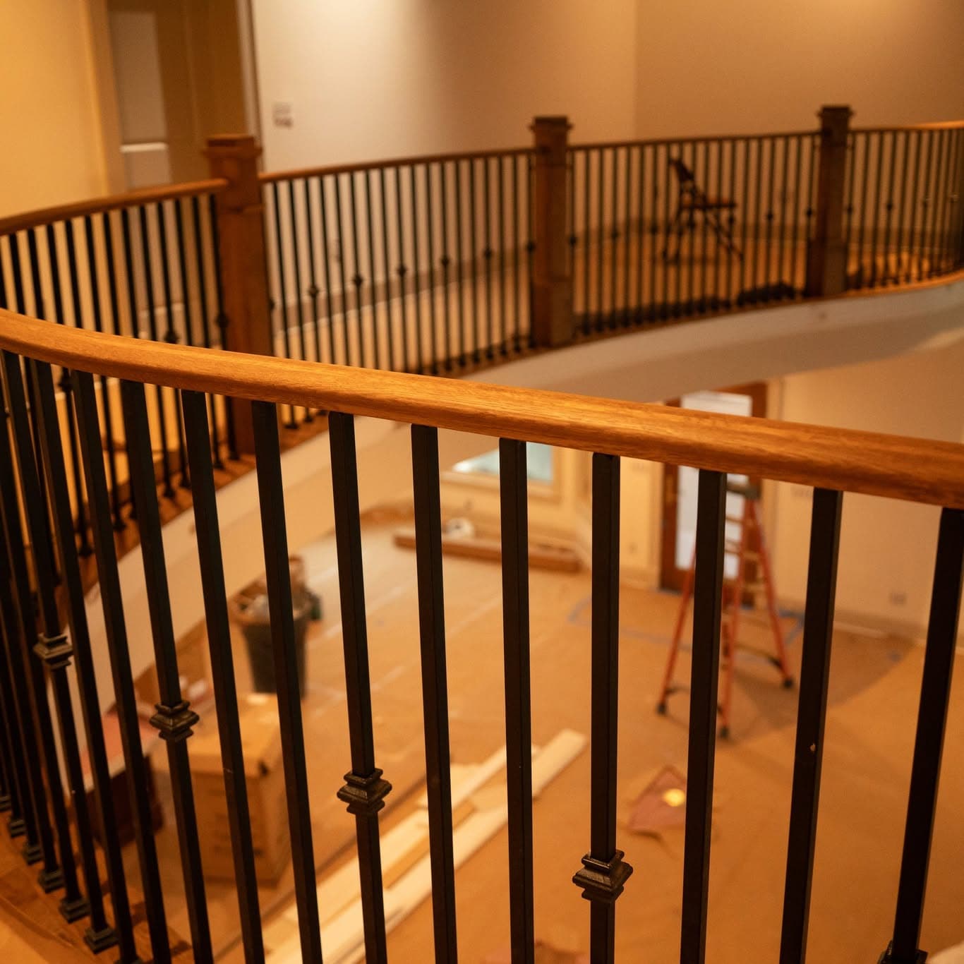 Curved hardwood balcony rail with square wood newels and matte black metal balusters, a job by Alabama Hardwood Restoration