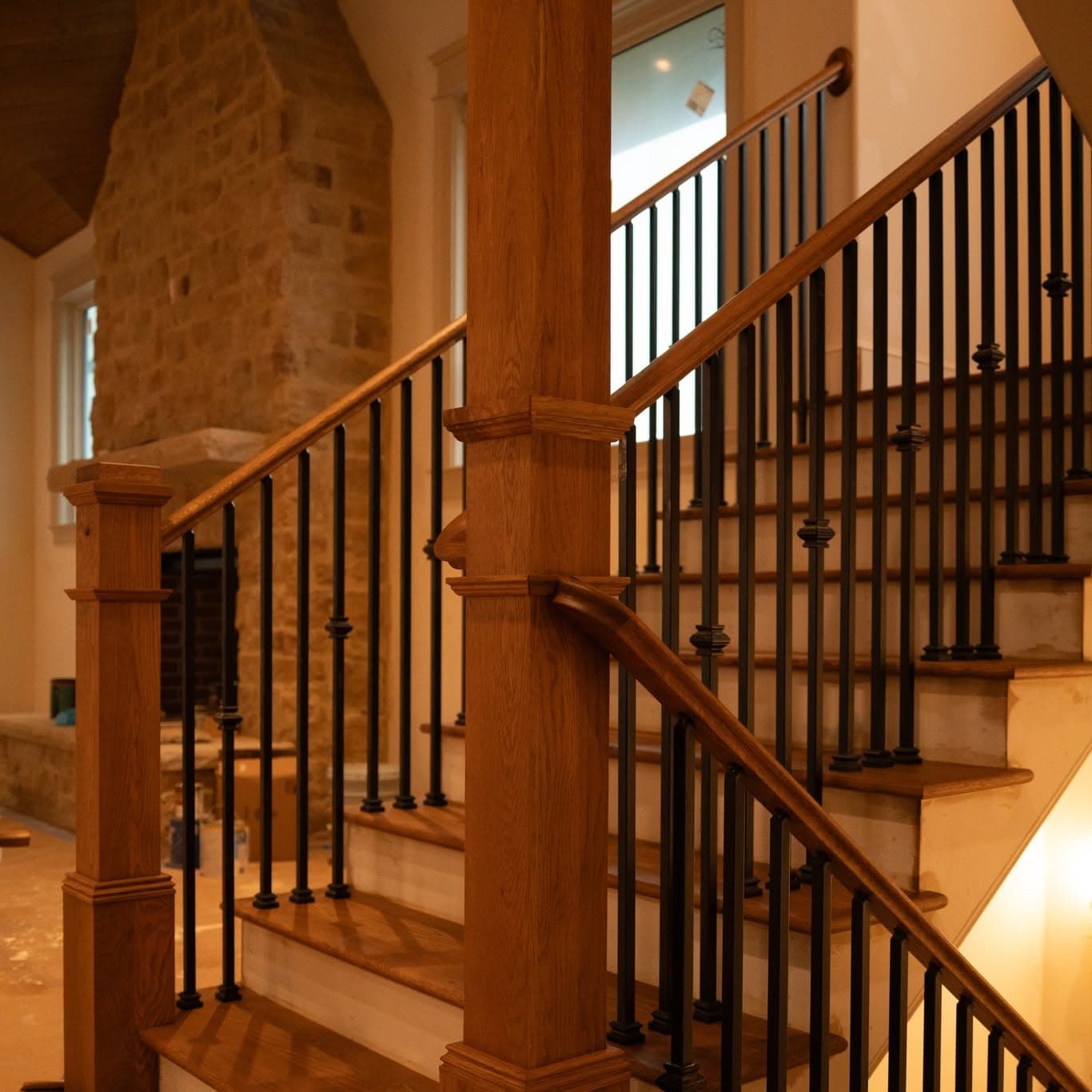 Split-level hardwood stairs with matching newels and black metal balusters, a job by Alabama Hardwood Restoration